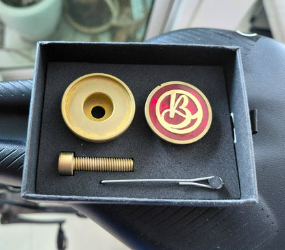 Titanium monogram stem top cap set in a gift box on a bicycle saddle.