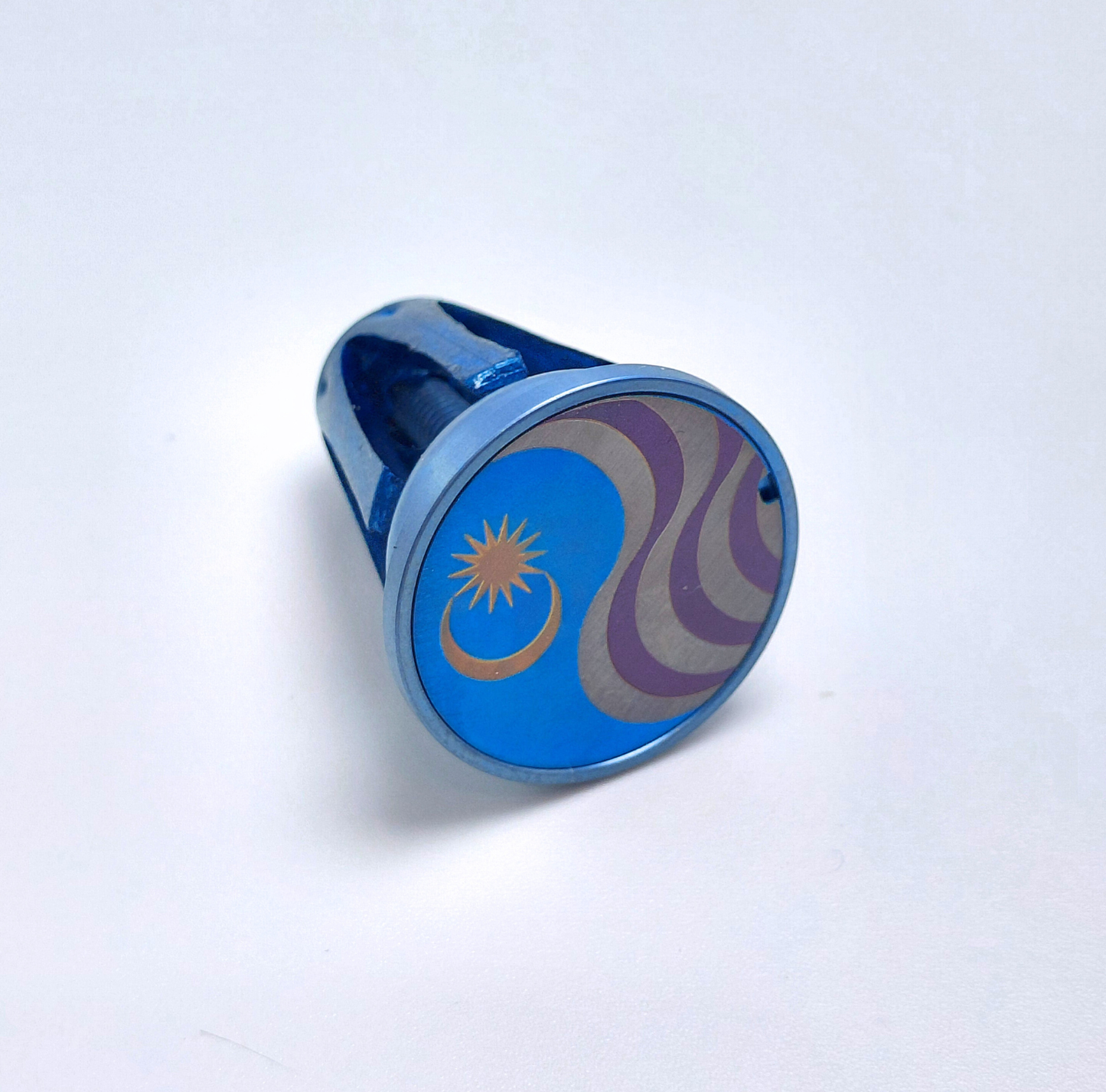 Blue and gold anodised Titanium with Malaysian flag design on a light blue background
