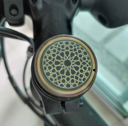 Close-up of a titanium stem cap in bronze and gold with Islamic pattern on a blurred background 
